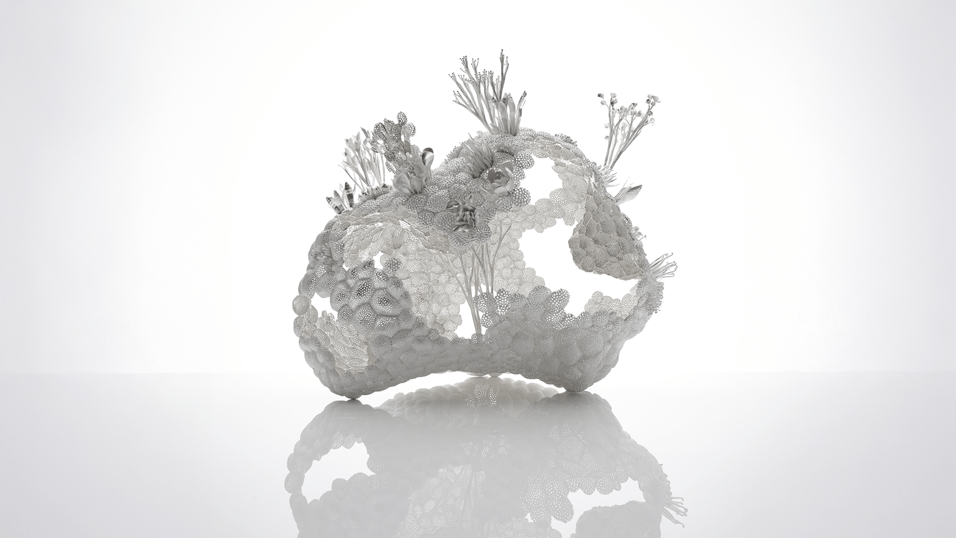 A piece from Junko's Uncontrollable Beauty series called Cloud/Tanka with a surface of intricate pierced disks with delicate leaves and flowers welded onto them.